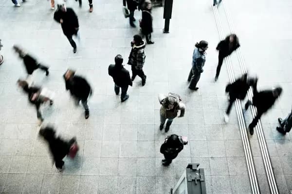 Menschen überqueren eine Bahnhofshalle, von oben gesehen